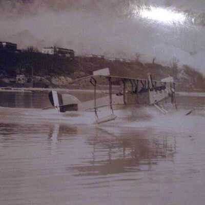 Two aviators and a biplane in motion on Lake Michigan
