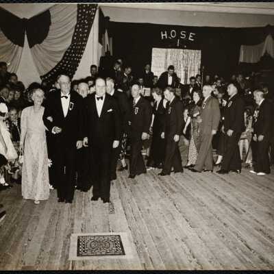 Chief of firedept. Dr. + Mrs. W. B Segur leading grand march. (The man on Segur's left is McEnelly leader of the orch.)
