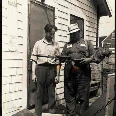 Hanna shows assistant(?) new rifle he is delivering to one of his customers. (At Bristol Mills)