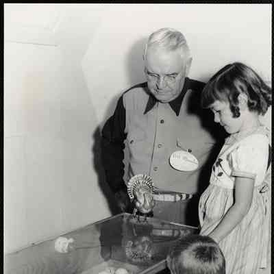 Eastern States Exposition. Mass. State Building. Bill Monehan of the Mass. Turkey Growers Association showing Karren Cote of Keene, N.H. and John Niedzwick of New Britian, Conn how the turkeys break out of their shells. Mass. Turkey Growers Assc. display.