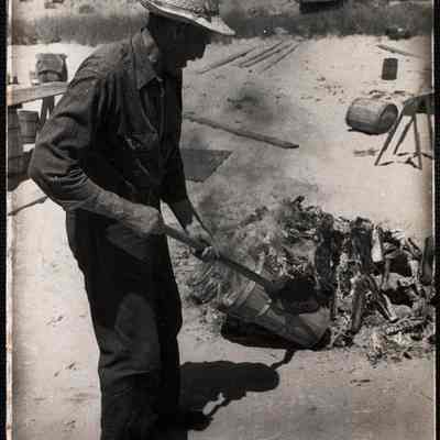 Nantucket clam bake Jim Coffin feeding the fire to heat the stones.