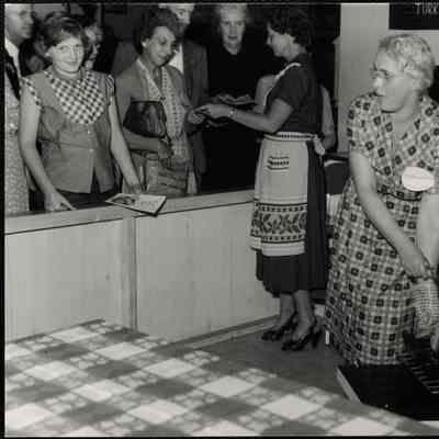 Eastern States Exposition. Mass. State Building. Mrs. Joseph Davis, demonstrating the proper way to roast a turkey while Mrs. Donald Sistare (Paxton, Mass.) passes out folders. This is at the Mass. Turkey Growers display.