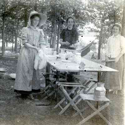Women cleaning dishes at a camp site.