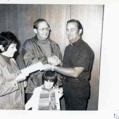 Edith and Ed Kubiak and daughter Patti receive savings bond from Fr. Romps