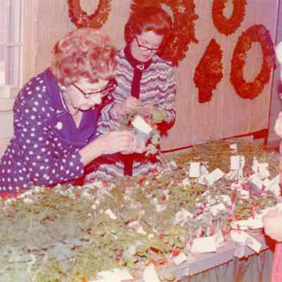 Vera Bunnett and Irene Stein arranging green plants and herbs.