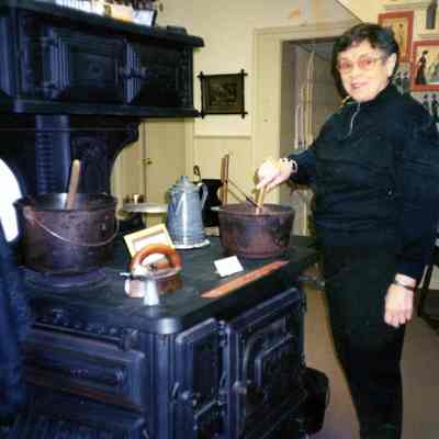 Virginia Presson using the cast iron kitchen stone on loan from Sanders at the Wayne Historical Museum.