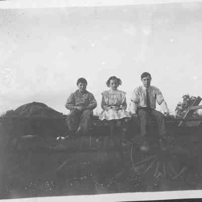 Three kids sitting on a wagan.