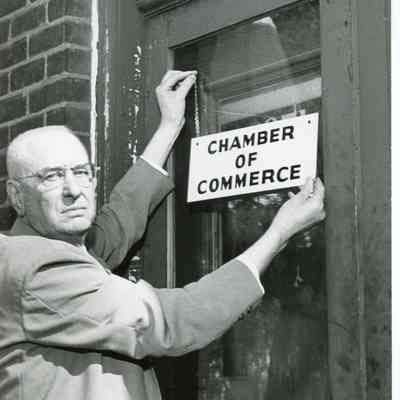 Hanging Chamber of Commerce sign on front door 1962