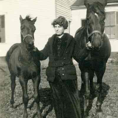 Woman holding two horses