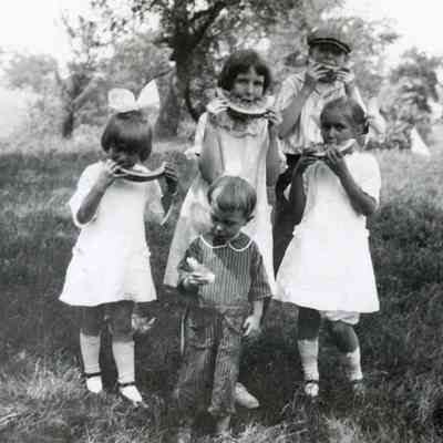 Children eating watermelon at a picnic.