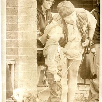 "Dogs Day" - Woman holding dog on leash; she is talking to boy in fireman's hat