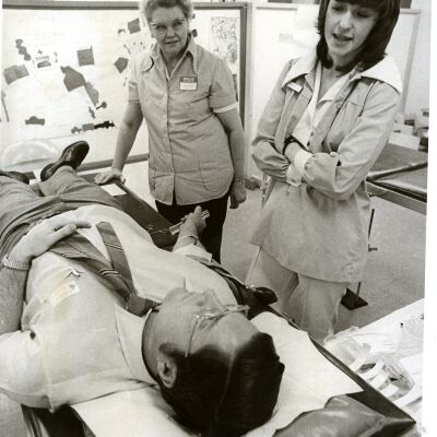 Man on hospital bed with two medical personnel (women) standing by
