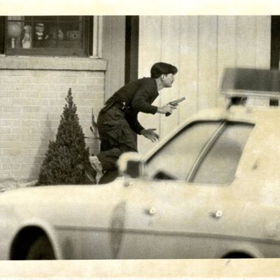 Police officer or security guard holding gun, alert pose