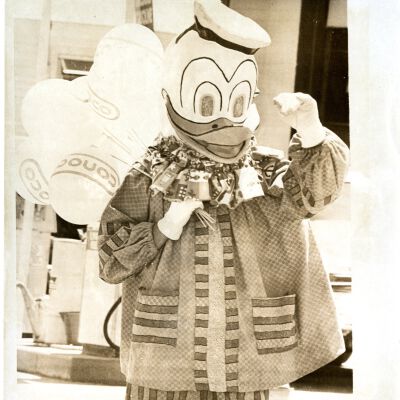 Adult in Donald Duck Costume, Holding Conoco balloons