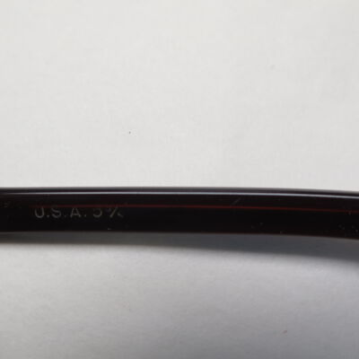 Text on sunglasses.: Origsize: 1" (h) x 2.5" (w) x; Origformat: Artifact