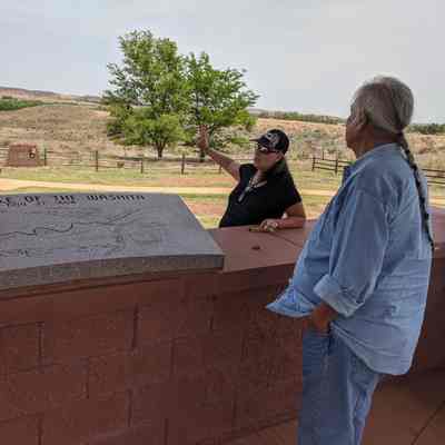 Lori Lane (from the Confluence group in Broomfield) and Frank Medicine Water (Cultural Coordinator for the Cheyenne and Arapaho Nation) look out over the Washita Site (1868): The Washita Battlefield National Park Service site is in western Oklahoma. The group from Broomfield visited this site. Frank Medicine Water guided the group on the visit. He shared that most Cheyenne and Arapaho view the event as a massacre, not a battle. May 2022