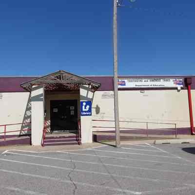 The exterior of the Public Library at Concho, tribal headquarters for the Cheyenne and Arapaho of Oklahoma. Note the seal and names on the sign to the top right of the building.: May 2022