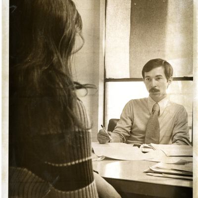"Dan Schuler speech" and "A new approach" - man at desk talking with young woman