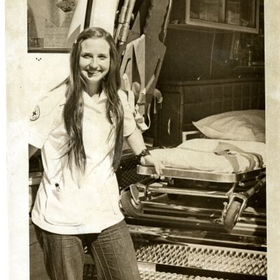 Young woman EMT? standing next to back of ambulance