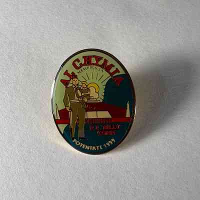 Pin: Shriner. Shriner holding child. building and sun rays in the background. "Al Chymia/ R.E. "Billy" Conn/ Potentate 1999" Donated by PGM James O. Wood (1999)