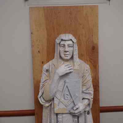 Statue: Mason painted white holding book with the compass symbol on it, nailed to plyboard.