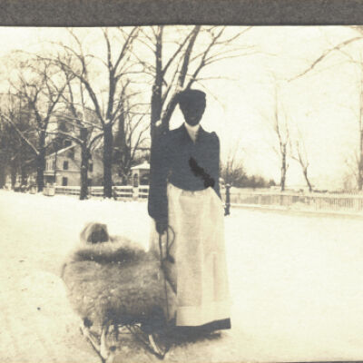 unidentified woman pulling child's sled in snow