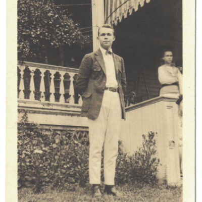 John C. Holmes in front of porch