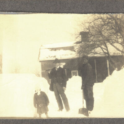 two men and child in snow in front of Holmes Barn