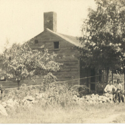 Peterson's House at Bedford Center with two men sitting on stone wall