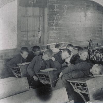 Schoolhouse Interior, 1892, Boy leaning on desk has just been caned.