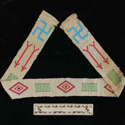 Here, the entire design of the belt can be seen. Includes blue symbols, red arrows, red diamond shapes and green linear patterns, all beaded.