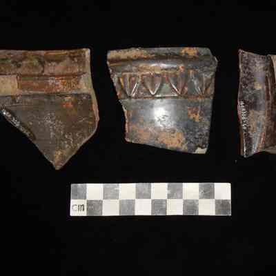 Repetitive triangle/leaf pattern on a brown-slipped, glazed coarse earthenware jar.