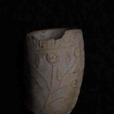 Flower motif embossed on side of pipe. Mold seam around edge.