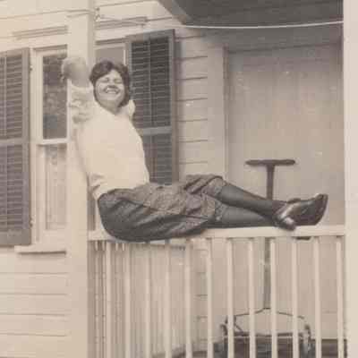 Woman sitting on porch railing