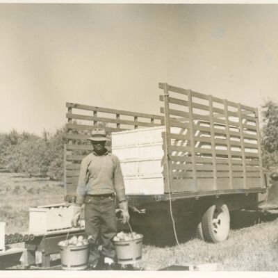 Black farmworker holding apple buckets