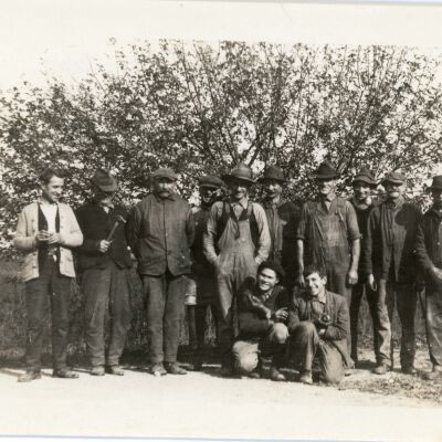 Farm workers in front of apple tree.