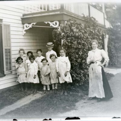 Unknown children and women outside a house