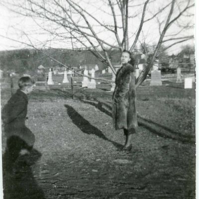 Woman standing in a fur coat, cemetary in the back ground