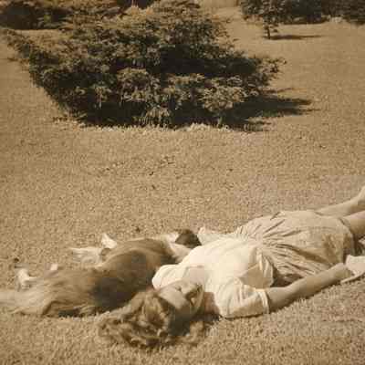Beth Mead as a young woman, lying on grass with dog