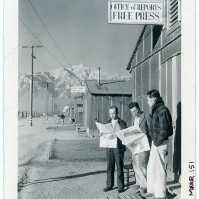 Roy Takeno (Editor) and group reading Manzanar paper [i.e. Los Angeles Times] in front of office, Yuichi Hirata, Nabuo Samamura