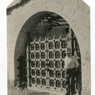 "Death Valley Scotty" by hand wrought iron gate of his castle, Death Valley, Calif.