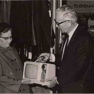 A photo view of Alfred Senter presenting a prize to Mrs. Jessie Hall.