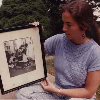 A photo view of a woman looking at an old photo. 9/7/1990.