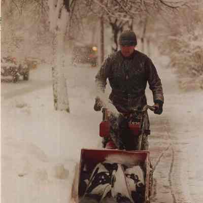 A photo view of a man snow blowing. 12/17/1987.