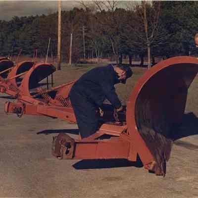 A photo view of a worker checking out snow plow blades. 11/10/1988.