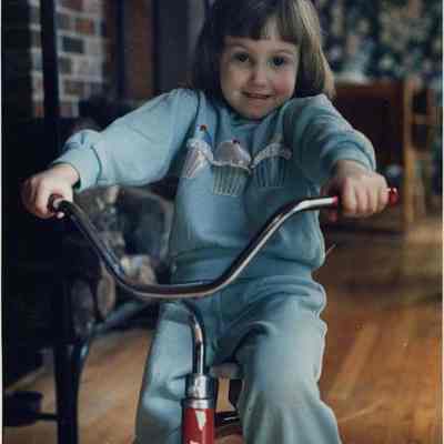 A photo view of a child on a tricycle. 4/3/1989.