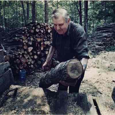A photo view of a man loading firewood. 6/20/1990.