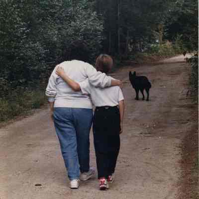 A photo view of two people and a dog walking. 9/27/1991.