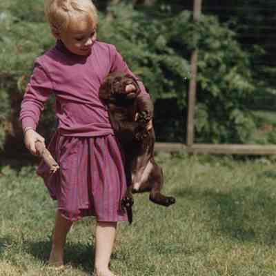 A photo view of a small boy carrying a puppy. 7/21/1989.