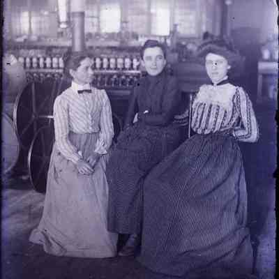 Three women sitting in a factory.